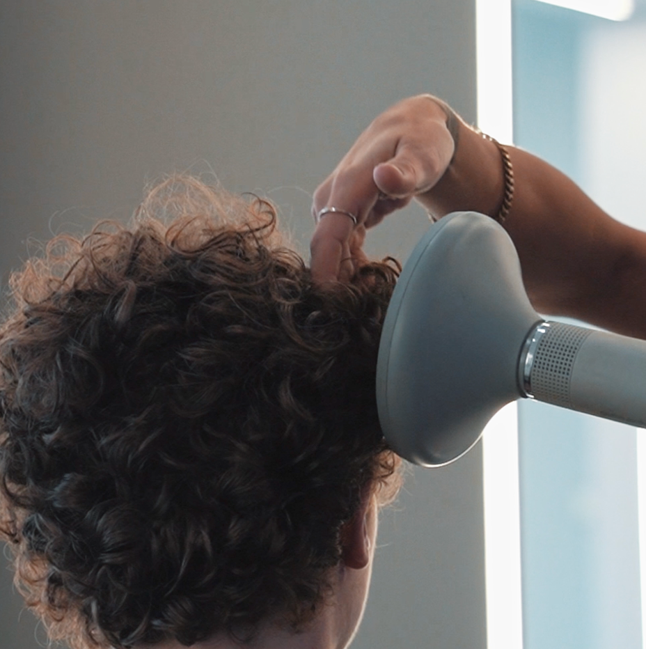 Black bottle of sea salt hair foam on sand.