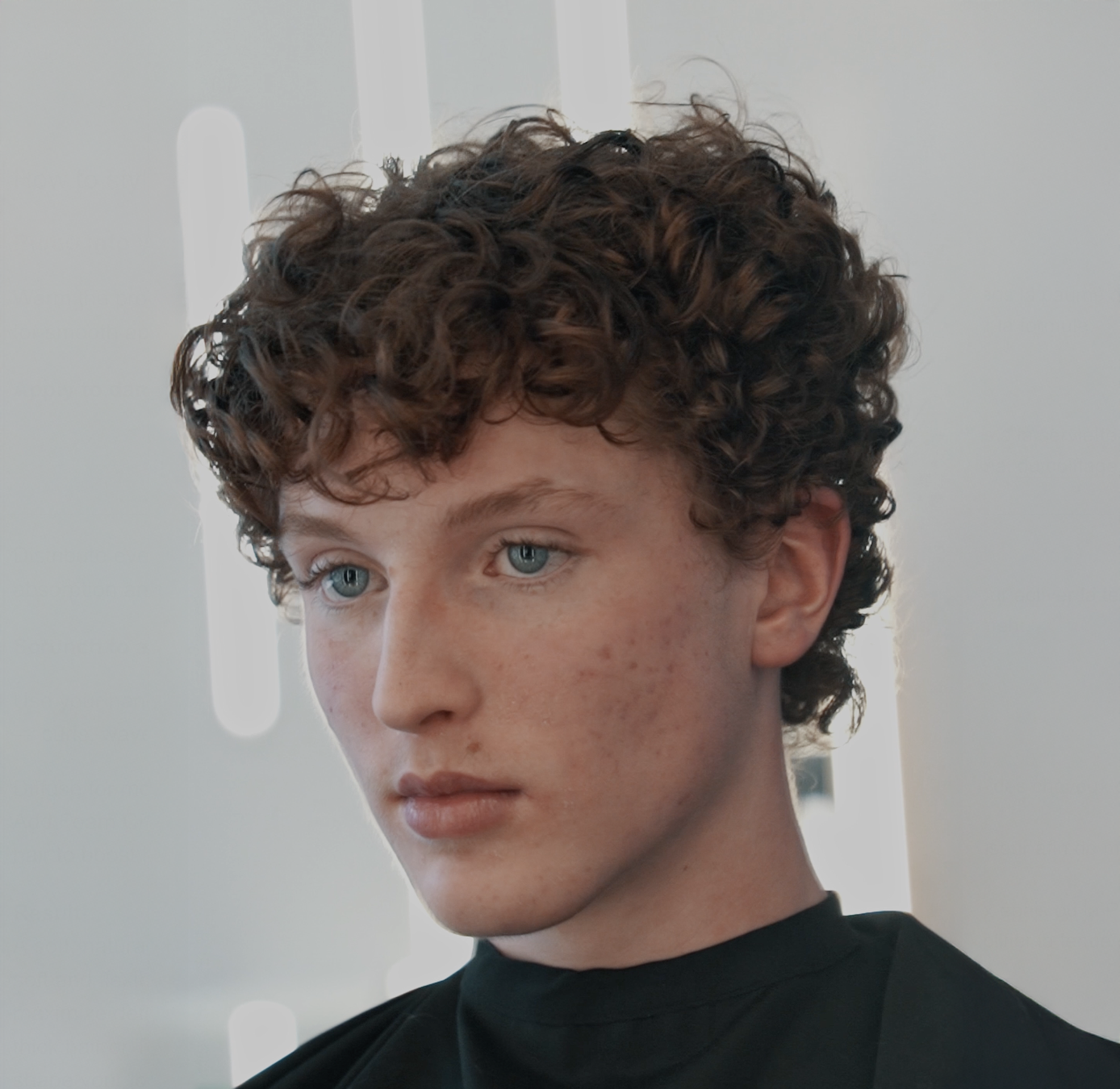 Man in a denim jacket resting his head on his hand, looking at the camera.