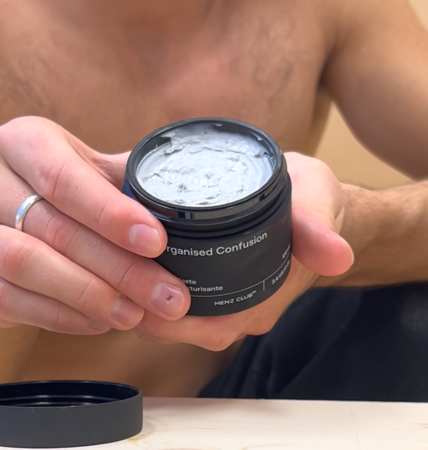 A person holding a black, water-resistant MENZ CLUB product in their hands.